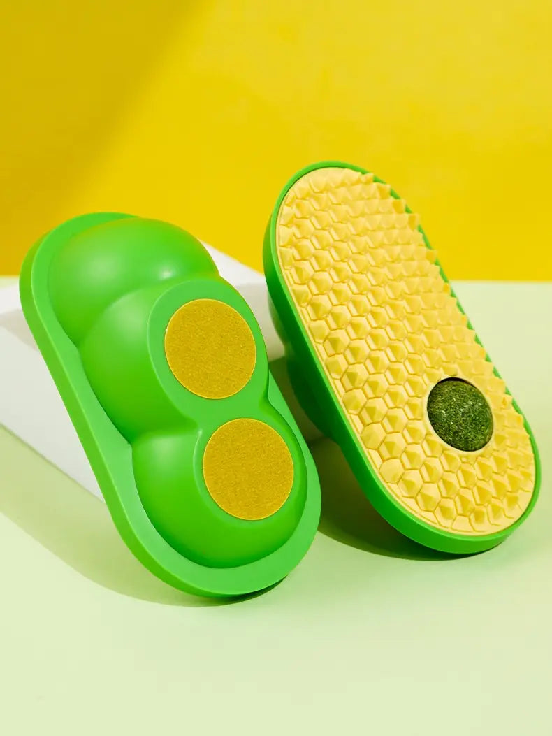 Grüne, avocadoförmige Katzenbürste zur Selbstpflege und Silikon-Kratzspielzeug mit einer gelb strukturierten Sohle mit kreisförmigen grünen Akzenten.
