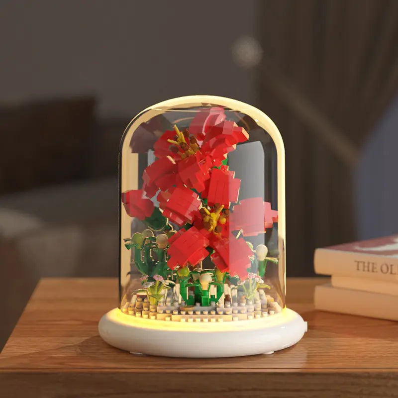 Un arrangement floral LEGO rouge éclatant affiché sous une coupole en verre transparente, avec un éclairage LED chaud, comme décoration jouet de dôme en verre pour fleurs, bloc de construction, éclairage LED.