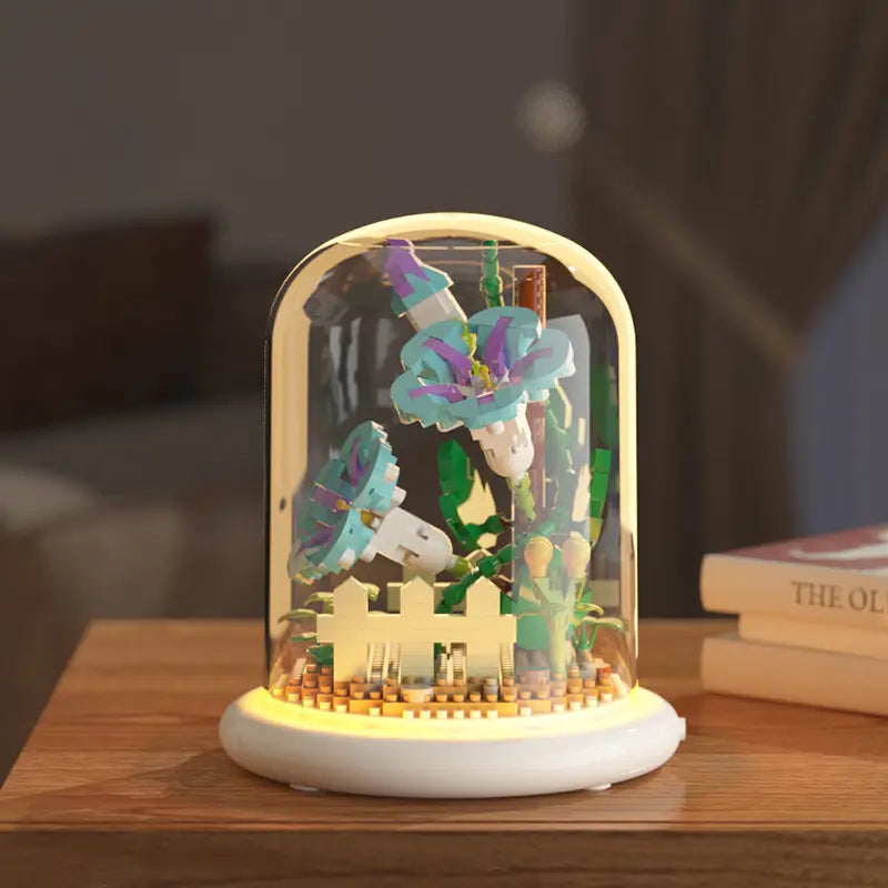 Une scène de jardin miniature de style LEGO, finement détaillée, à l’intérieur d’une coupole en verre transparente, avec une base chaleureusement lumineuse, comme décoration jouet de dôme en verre pour fleurs, bloc de construction, éclairage LED.
