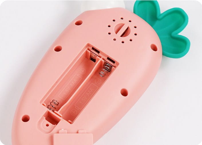 Baby toy phone carrot shape educational music toy in pink plastic with green leafy top and visible battery compartment on the back side.