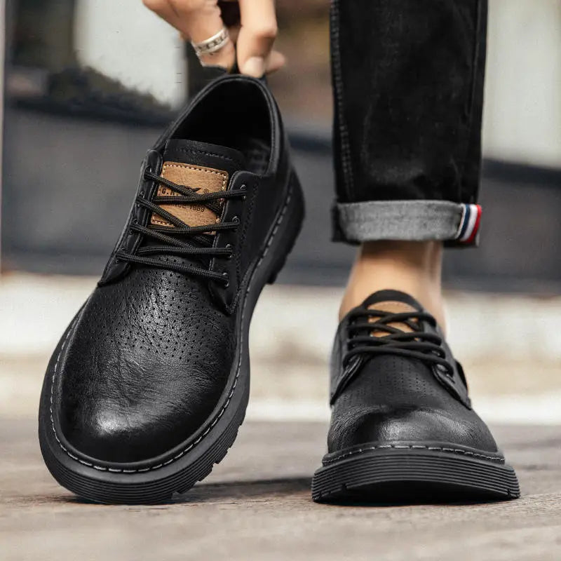 Black leather lace-up men’s business casual shoes with perforated detailing and a thick rubber sole.