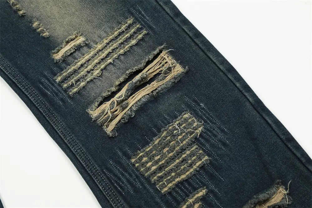 Jeans en denim déchiré homme à effet usé, jambe droite, couleur foncée, avec bords effilochés et coutures visibles.