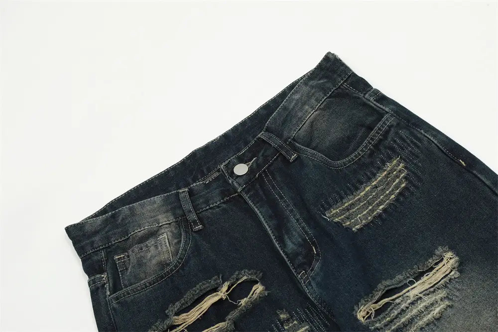 Jeans déchirés homme à effet usé, jambe droite, en denim foncé, avec des détails de déchirures et des bords effilochés.