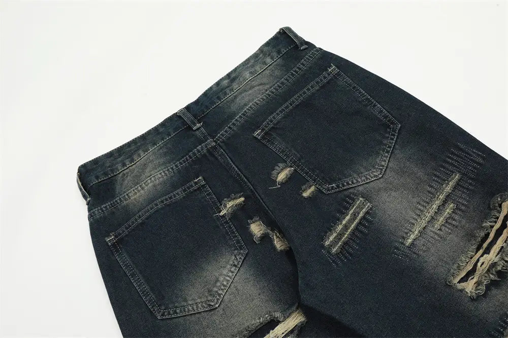Jeans déchirés homme à effet usé, jambe droite, en denim, présentant des détails de déchirures et des bords effilochés.