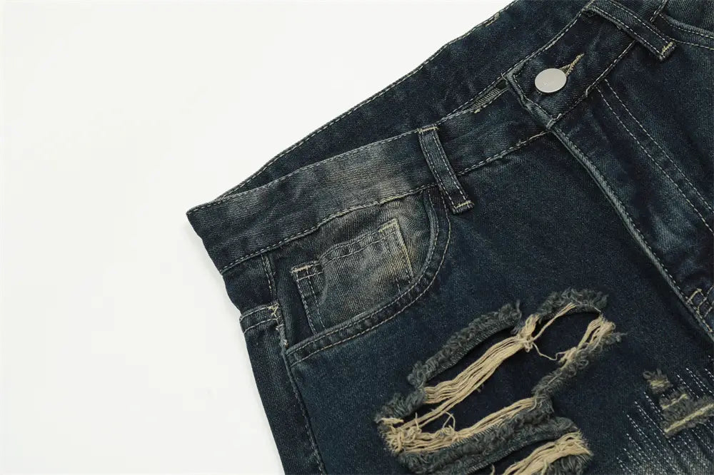 Jeans déchirés homme à effet usé, jambe droite, en denim, comportant des zones de genou déchirées avec des bords effilochés et des coutures visibles.