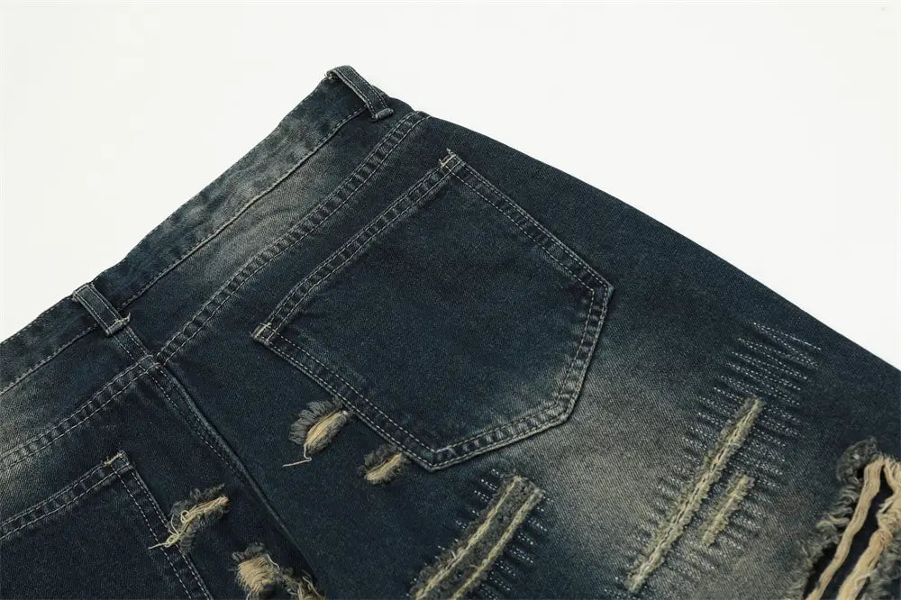 Jeans déchirés homme à effet usé, jambe droite, en denim, présentant des détails de déchirure, des bords effilochés et des coutures visibles.