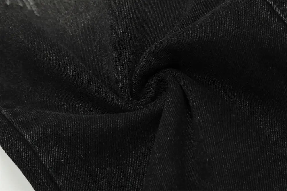 Tejido de los vaqueros negros de mezclilla con pernera recta y estilo desgastado para hombre, con aspecto ligeramente desgastado y con textura.