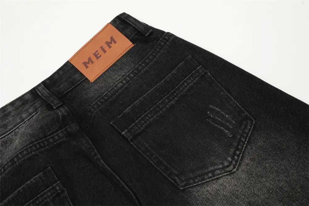 Los vaqueros negros de mezclilla con pernera recta y estilo desgastado para hombre, mostrados desde la parte posterior, con un parche de marca de cuero marrón con la inscripción «meim» bordada en negro.