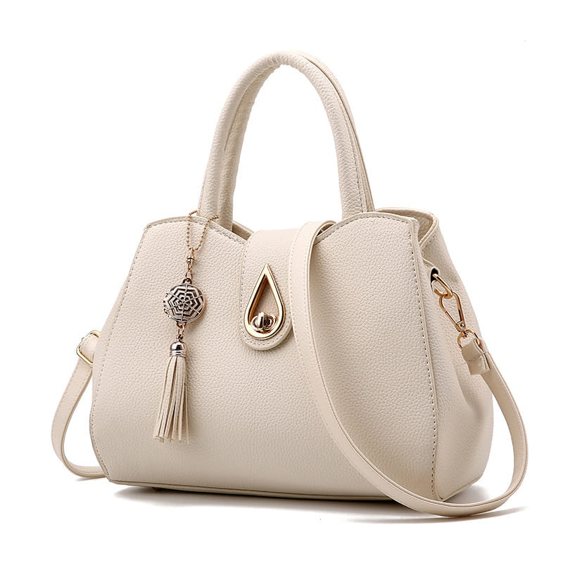 Ecrufarbene Ledertasche mit Quaste für Damen aus geprägtem, genarbtem Leder mit einem großen Schultertaschen-Design, goldfarbenem tropfenförmigem Verschluss und dekorativem Quasten-Anhänger.