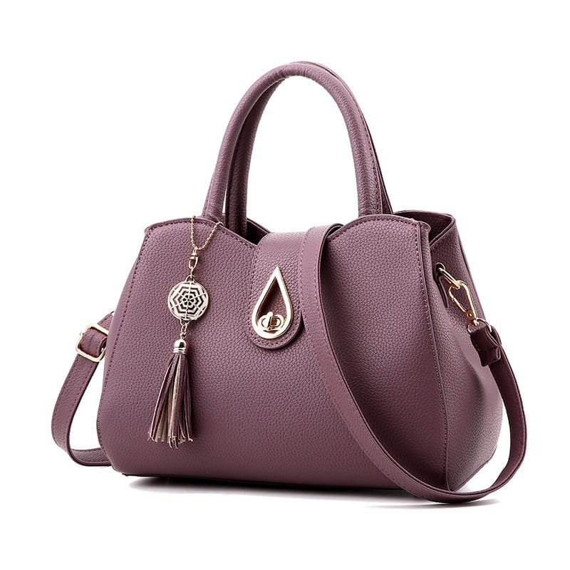 Lila strukturierte Ledergroßtastchen Schultertasche für Damen mit goldfarbenem tropfenförmigem Verschluss und dekorativem Quasten-Anhänger.