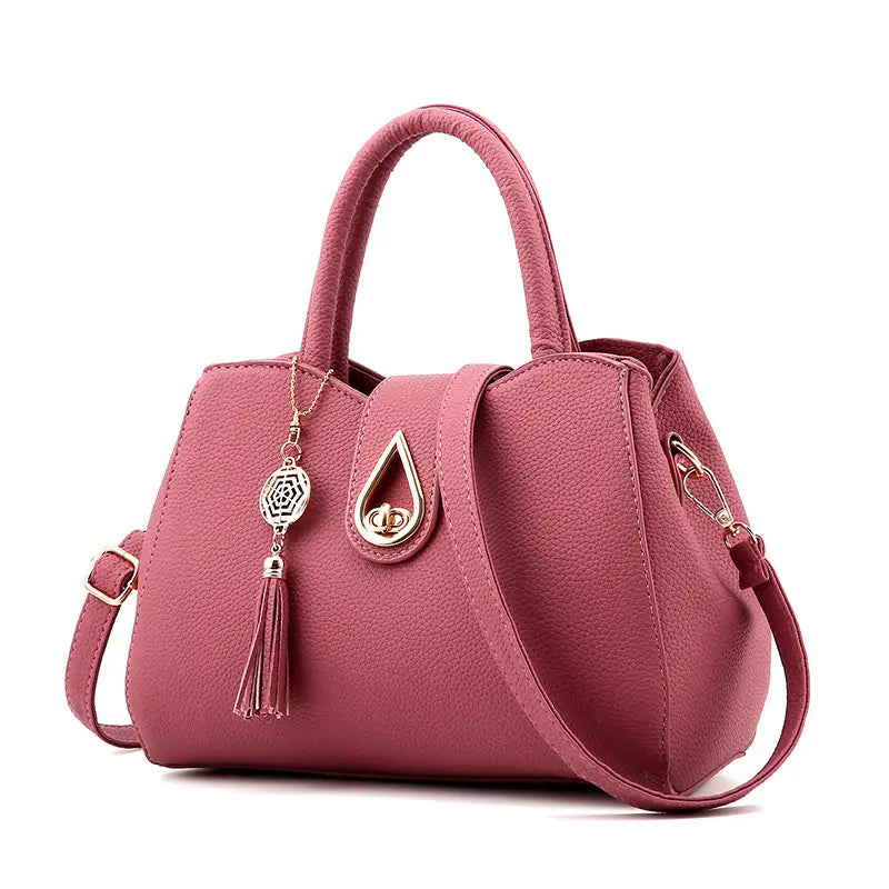 Eine rosa strukturierte Ledertasche mit Quaste für Damen mit goldfarbenem tropfenförmigem Verschluss und einem Design als große Schultertasche.