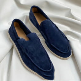 Mocasines tipo slip-on de ante azul marino para hombre con suelas de goma blancas, diseñados como calzado casual.