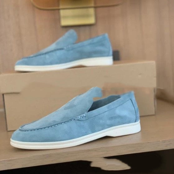 Mocasines de ante para hombre en azul claro con suelas de goma blancas, diseñados como calzado casual.