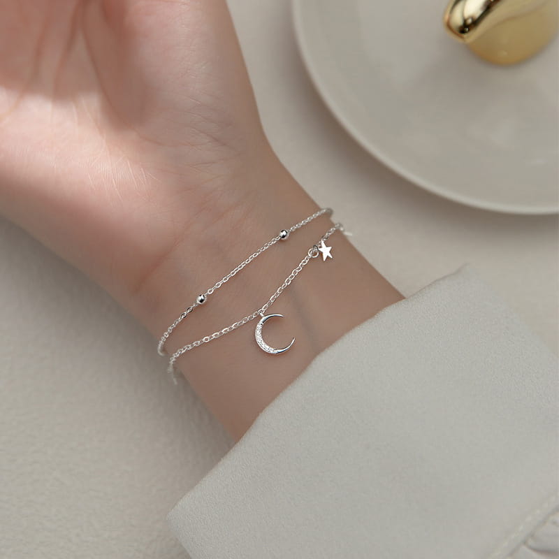 Delicate silver-toned double-layer anklet bracelet featuring a crescent moon charm, star accent, and tiny spherical beads.