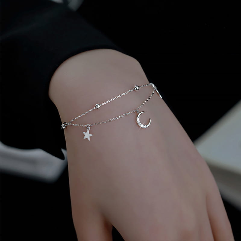 A delicate silver double-layered anklet bracelet featuring a moon and star crystal charm.
