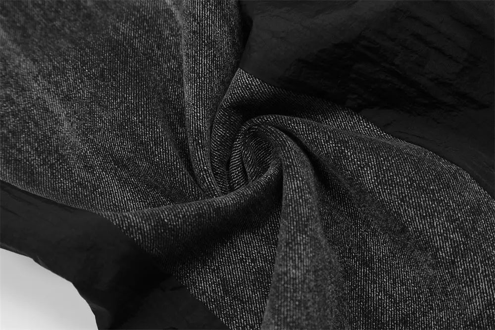 Joggers de mezclilla para hombre con panel de contraste y cintura elástica confeccionados con tela texturizada gris oscuro, con un brillo sutil y un patrón tejido con ligeros pliegues.