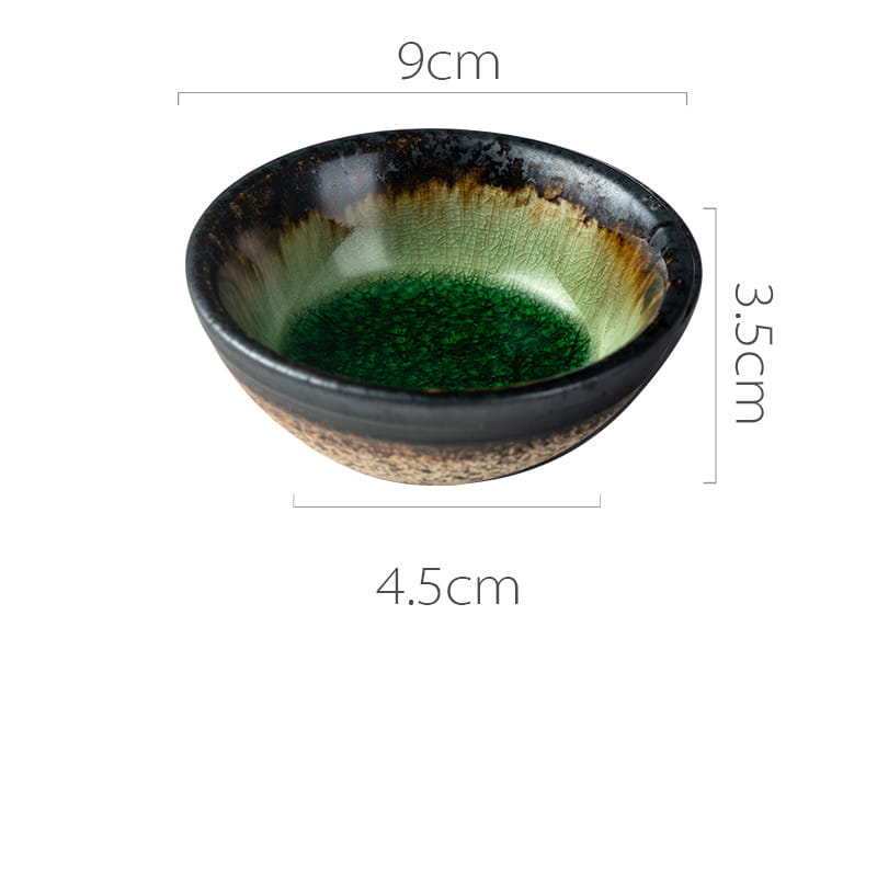 A handcrafted Japanese ceramic small plate featuring a rustic speckled glaze with a glossy black rim transitioning to vibrant green and earthy brown inside.
