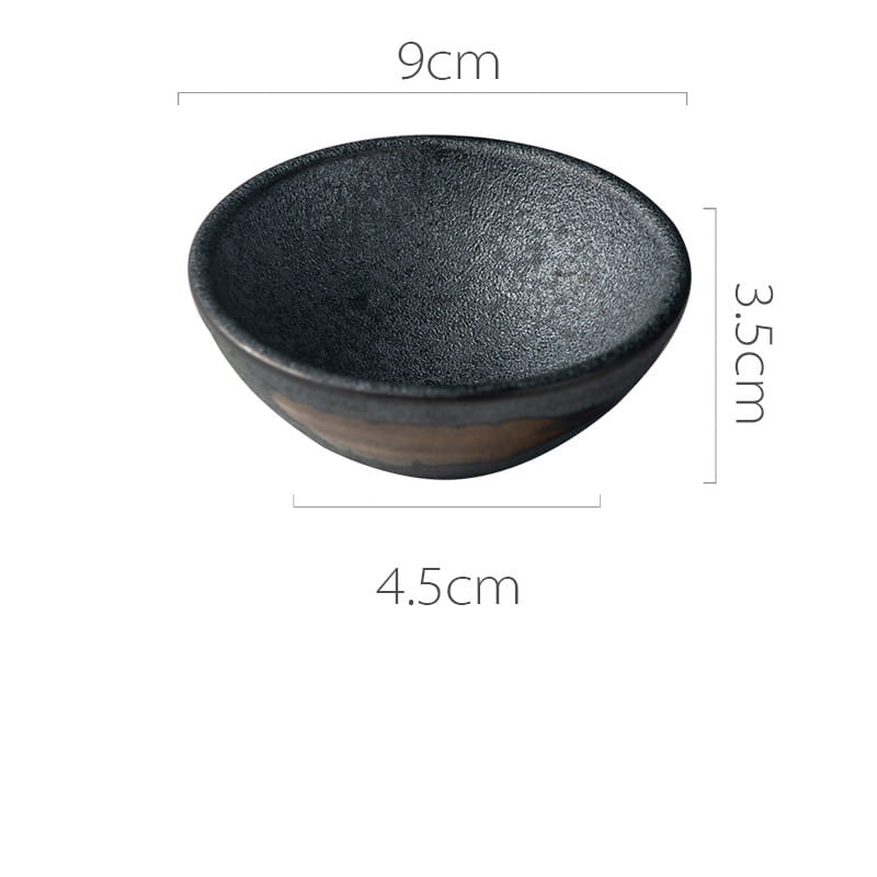 A small matte black ceramic bowl with a textured interior and a subtle brown rim featured in the Japanese ceramic small plates rustic speckled glaze collection.