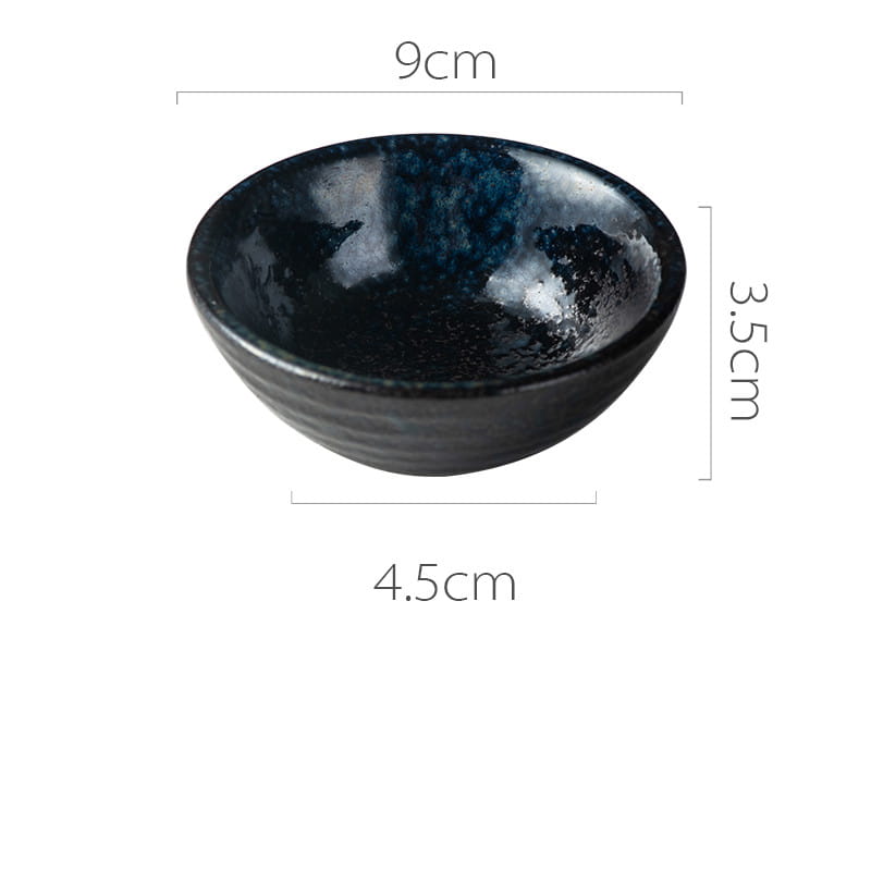 A glossy black Japanese ceramic small plate featuring a rustic speckled glaze with a textured interior and subtle horizontal ridges around its rim.