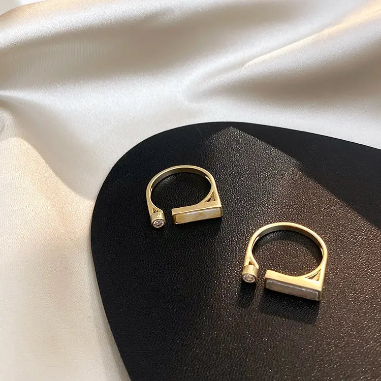 Gold-toned open vintage geometric zircon marble adjustable ring with a rectangular light-colored stone and a small clear gemstone accent.