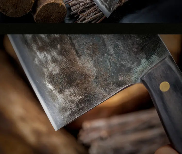 Ein stark abgenutztes dunkelgraues, handgeschmiedetes Hackbeil aus hochwertigem, kohlenstoffreichem Edelstahl mit einem schwarzen Holzgriff und einer goldfarbenen Niete.