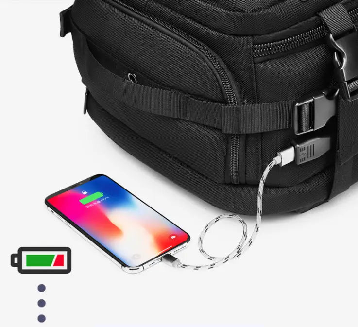 black tactical waterproof laptop backpack with integrated usb charging port and cable shown powering a smartphone from the back side