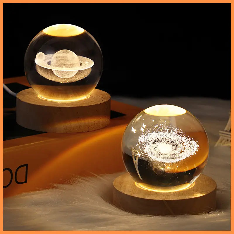 3d galaxy crystal ball led night light with a transparent glass spherical lamp featuring a laser-engraved planet or galaxy design emitting a warm yellow soft glow.