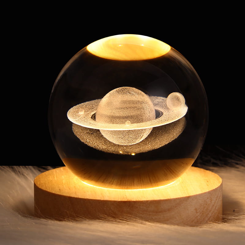 A warm-glowing 3d galaxy crystal ball led night light moon lamp featuring a transparent spherical glass design with an intricately detailed saturn and small moon inside, set on a polished wooden base.