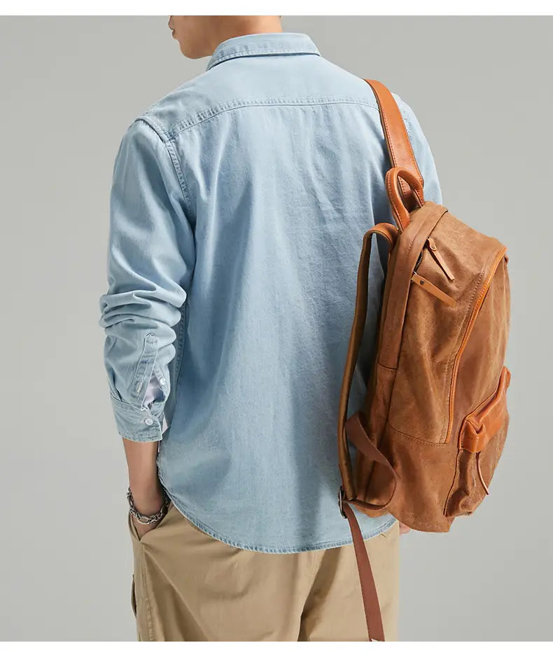 Rucksack aus beigem Leder mit sichtbarer Steppung und mehreren Taschen, kombiniert mit einem Herren-Langarm-Jeanshemd im Casual-Stil mit Knopfleiste