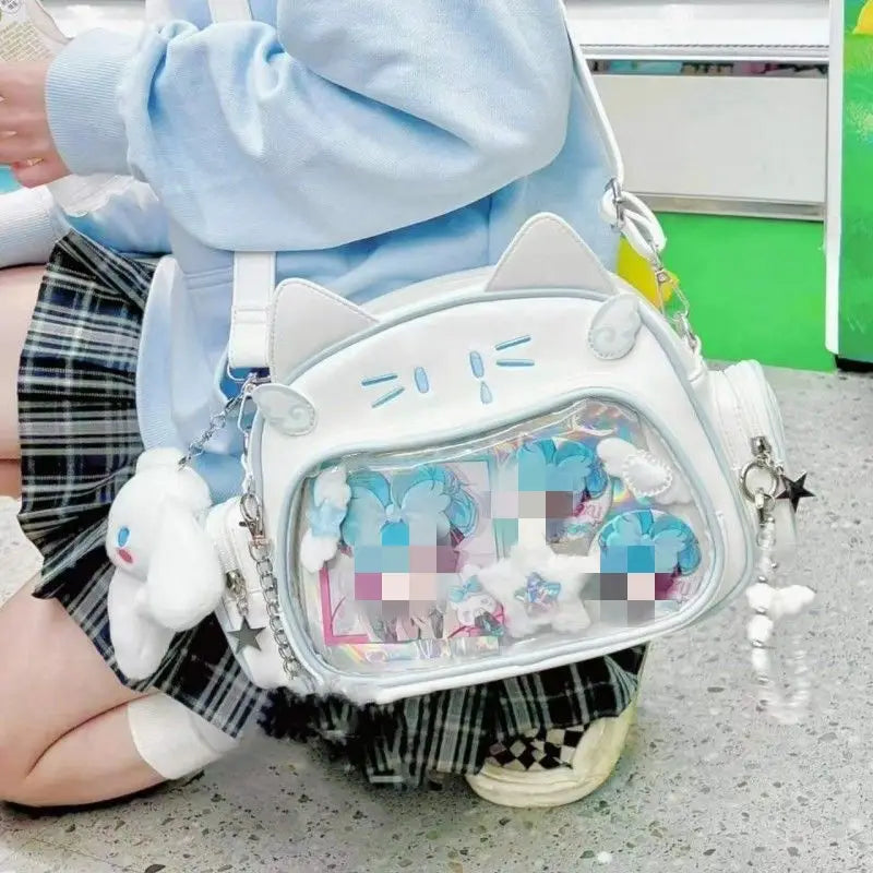 White cat-shaped crossbody bag with clear front panel and plush accessories designed as a cat messenger bag ita style accessory.