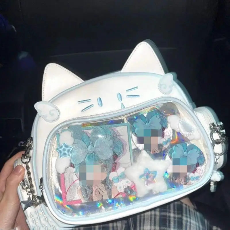 White cat messenger bag crossbody bag with clear ita panel front filled with blue and white glittery charms star shapes and holographic accents.