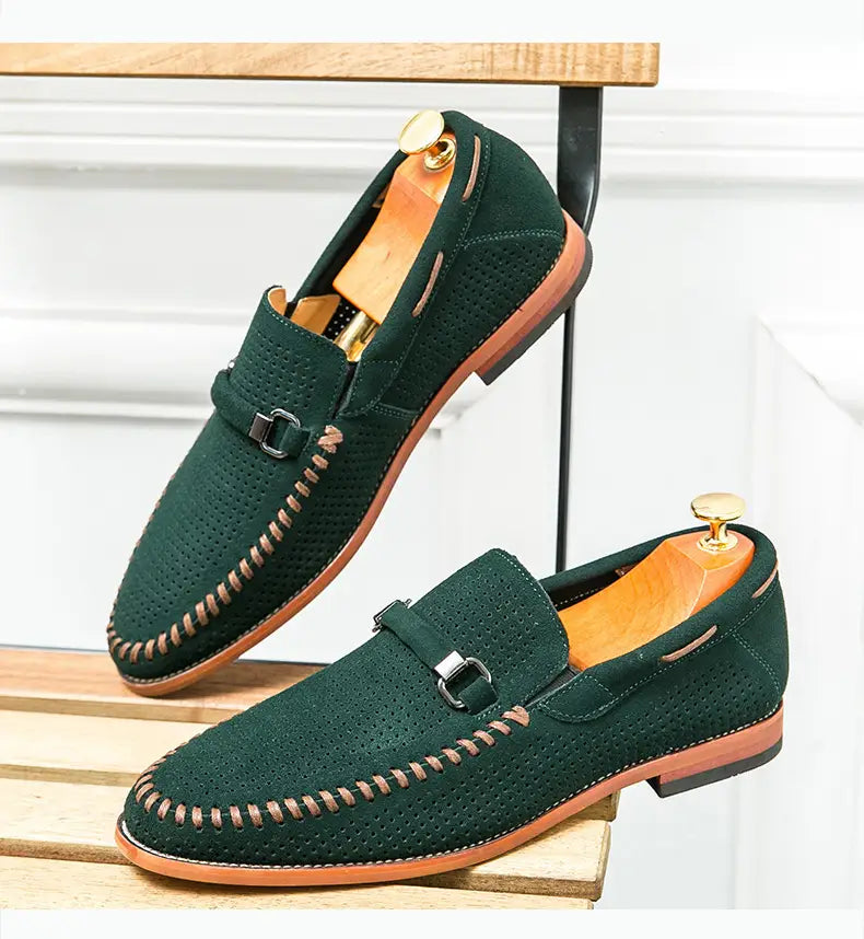 Mocasines de cuero verde oscuro hechos de ante perforado con costuras color camel y una suela marrón de contraste, estilo mule, cómodos al calzarlos.