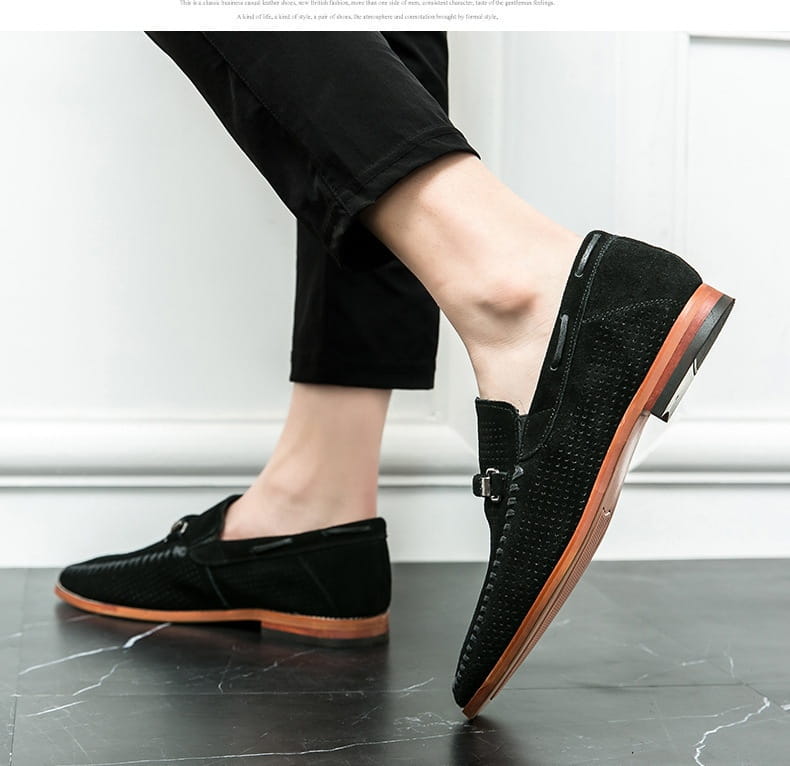 Mocasines de ante negro con perforaciones de cuero, con patrón texturizado y suelas de cuero marrón, diseñados como zapatos tipo mule.