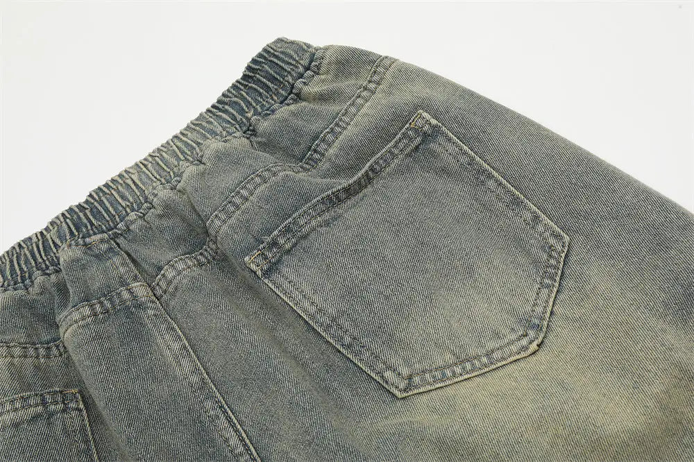 Shorts en jean à bretelles diagonales pour hommes, avec taille à cordon, en tissu denim gris, dotés d’une ceinture élastique et d’une finition délavée.