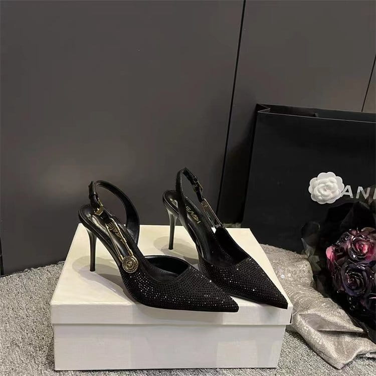 Black rhinestone slingback stiletto heels in black glittery satin with a gold-tone circular buckle and slender high heel.