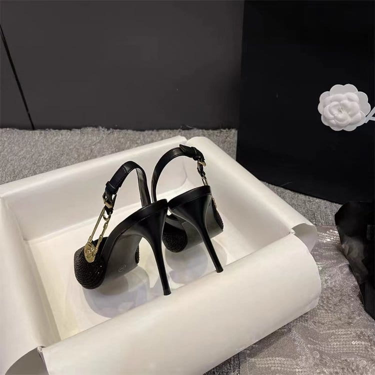 black rhinestone slingback stiletto heels with a sleek glossy finish and gold-tone hardware accents