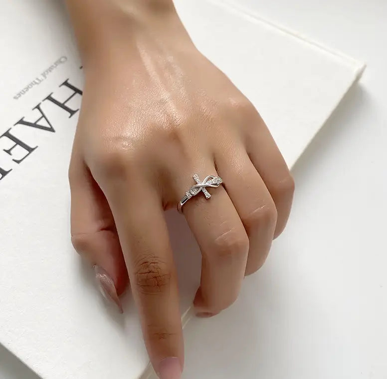 A delicate adjustable silver ring for women featuring a bow design adorned with sparkling clear crystals.