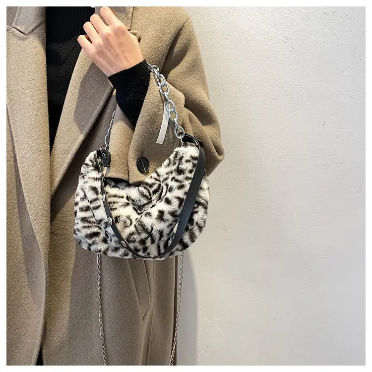 Plush animal print baguette bag featuring faux fur leopard print with a silver chain and black leather crossbody strap.