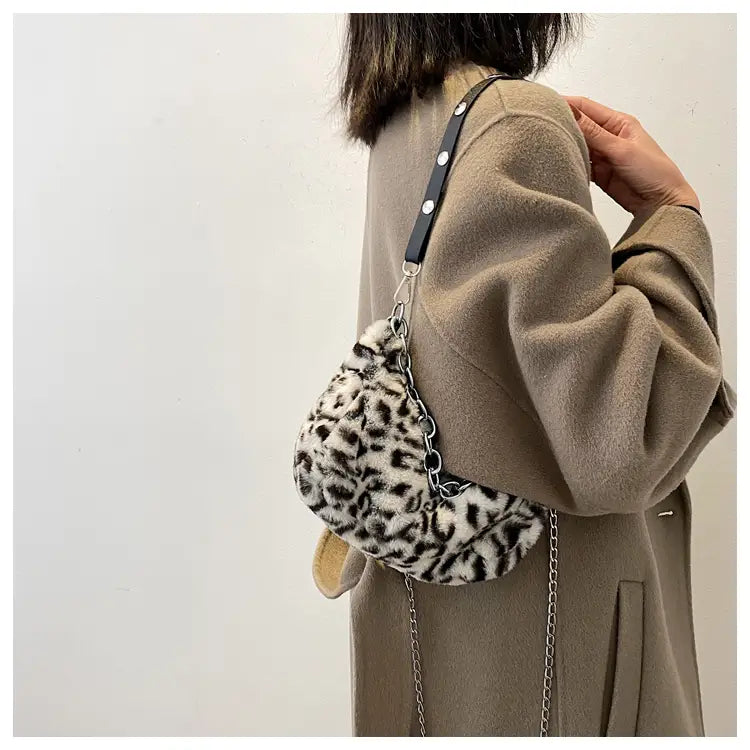 Plush animal print baguette bag featuring faux fur leopard print with black leather strap and silver chain accents.