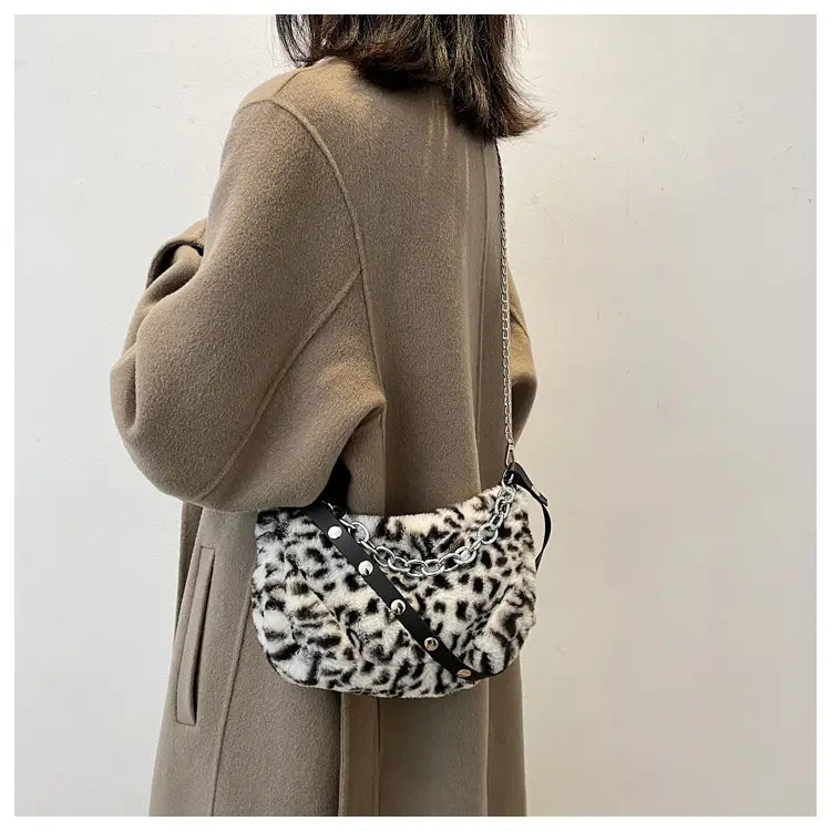 Plush animal print baguette bag featuring faux fur leopard print with black leather straps and silver chain accents.