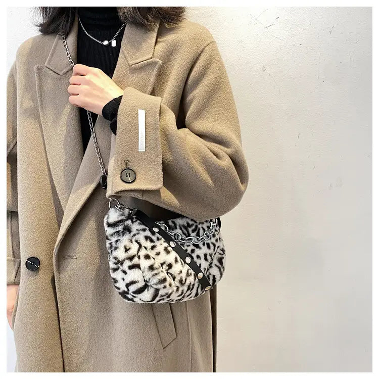 Plush animal print baguette bag made of faux fur with leopard print design featuring a black chain strap and silver hardware.