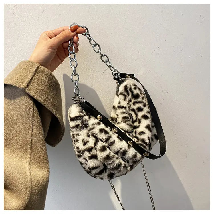 plush animal print baguette bag featuring faux fur leopard print with black leather straps and silver chain accents