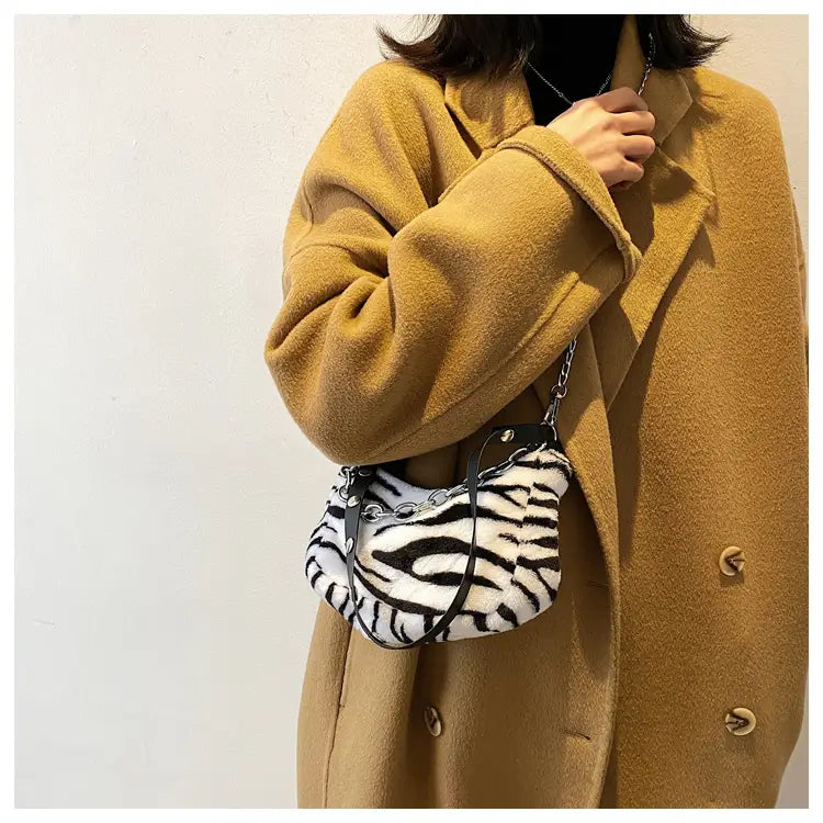 a plush animal print baguette bag featuring a black and white zebra-striped design with a silver chain strap