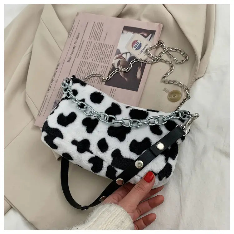 A plush black and white leopard print baguette bag with silver chain strap and black leather accents.