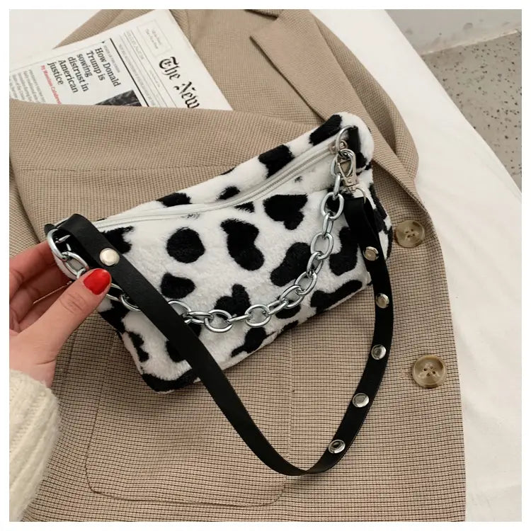 Plush animal print baguette bag featuring black and white leopard-print faux fur with a silver chain strap.
