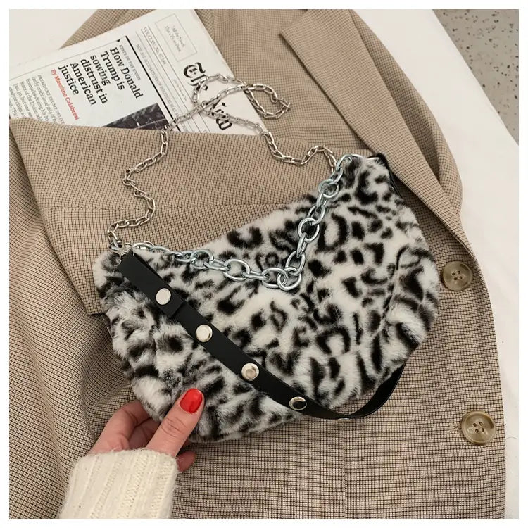 Plush animal print baguette bag featuring faux fur leopard print with black leather accents and a silver chain strap.