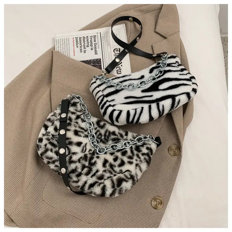 Two plush animal print baguette bags in zebra and leopard faux fur with silver chain straps displayed side by side.