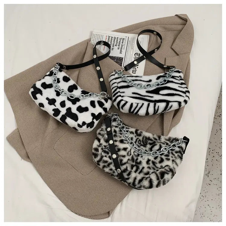 Three black-and-white plush animal print baguette bags with faux fur texture and silver chain straps featuring leopard zebra and cow patterns.