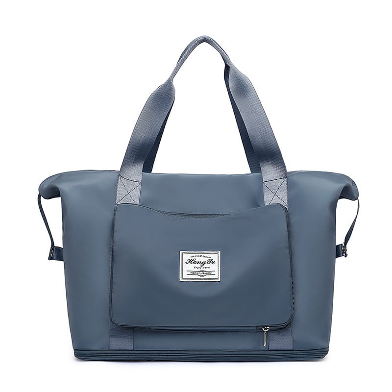 A sleek dark gray foldable gym bag waterproof travel duffel with reinforced handles front zippered pocket white label and shoe pocket.