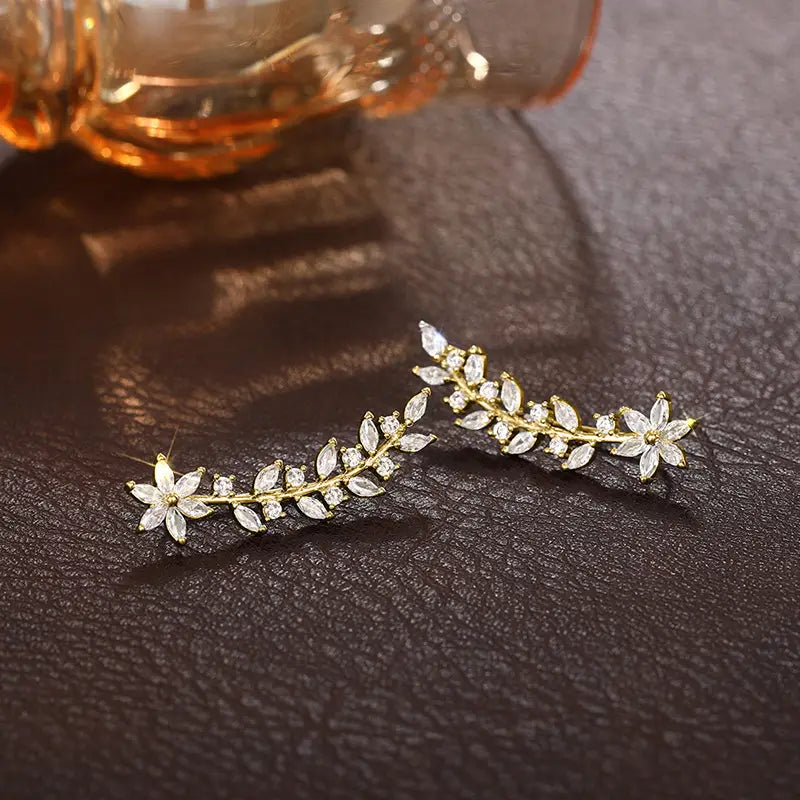 Crystal floral vine ear climber earrings for women featuring gold-toned leaf and flower design adorned with clear crystals.